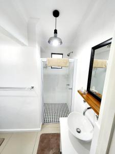 a white bathroom with a shower and a sink at Bayside Bliss Studio Apartment in Summerstrand