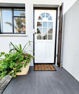 a white front door with a potted plant at Bayside Bliss Studio Apartment in Summerstrand