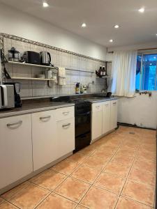 een keuken met witte kasten en een zwarte kachel bij Casa con pileta climatizada privada in Bariloche