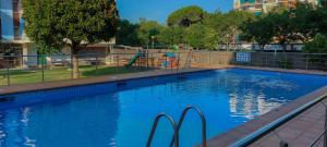 a blue swimming pool with a playground in the background at Vistes al mar Ideal per parelles i teletreball in Blanes