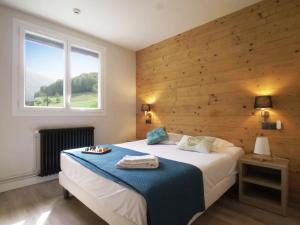 een slaapkamer met een bed met een houten muur bij Hotel Le Chalet in Sainte-Marie-de-Campan