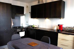 eine Küche mit schwarzen Schränken und einem Tisch mit Stühlen in der Unterkunft Superbe appartement ,6 pers, proche de Paris, dans résidence privée , parking et WIFI gratuits! ! in Vitry-sur-Seine