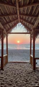 a sunset over the ocean from a beach pavilion at The Meraki Beach Resort in Gokarna