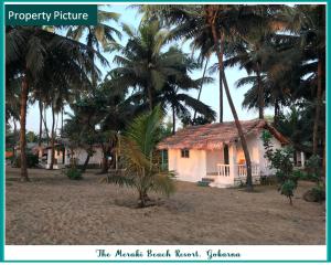 una casa en la playa con palmeras en The Meraki Beach Resort en Gokarna