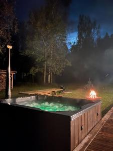 una bañera de hidromasaje en el patio por la noche en Salmiņu Pirtsmāja ar relaksējošu baļļu, en Pastva Barbern