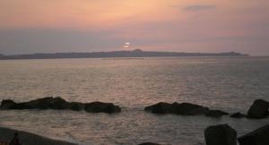 a sunset over the ocean with rocks in the water at Casa Vacanze Spadafora in Spadafora +3 photos