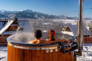 a man and a woman sitting in a hot tub at Hole in Zakopane