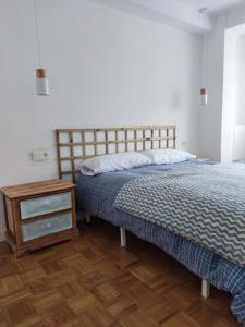 1 dormitorio con cama y mesita de noche de madera en La cámara secreta de BelNi, en Avilés