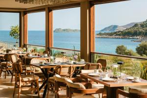 a restaurant with tables and chairs and a view of the ocean at Paramithenio Village Beach Resort & Spa in Agioi Apostoli