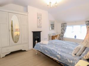 a bedroom with a bed and a mirror and a dresser at Kittiwake Cottage in Hunstanton