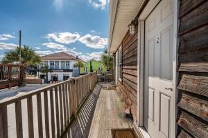 un portico di legno con una porta bianca su una casa di The Folly Feeling 1 Block to Beach a Folly Beach