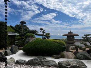 un jardín con un pequeño arbusto y una fuente de piedra en Villa SHINOBI -忍-, en Hinase