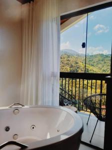 a white bath tub in a room with a balcony at Encontro dos Vales in Visconde De Maua