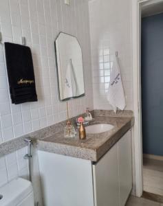 a bathroom with a sink and a mirror and a toilet at Porto Central Residence 01 in Porto De Galinhas