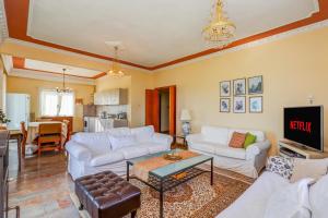 a living room with white couches and a tv at Country Home Genesi 20 min from Trikala in Genésion