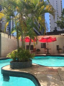a swimming pool with palm trees and red umbrellas at hotel italia beach fortaleza in Fortaleza