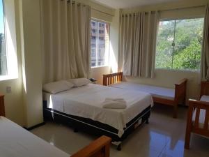 a bedroom with two beds and two windows at hotel italia beach fortaleza in Fortaleza