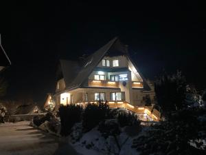 una casa illuminata di notte nella neve di Apartamenty u Magika a Zakopane