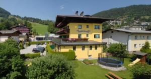 ein gelbes Haus mit Spielplatz in einem Dorf in der Unterkunft Hotel Pension Hubertus in Zell am See