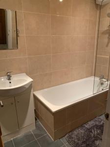 a bathroom with a bath tub and a sink at Cosy spacious master room. in London