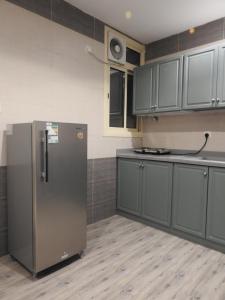a kitchen with gray cabinets and a refrigerator at نيو العرين بارك أبها in Abha