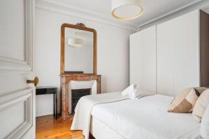 a white bedroom with a mirror and a bed at Luxury Apartment La Tour Paris in Paris