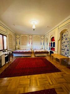 Habitación grande con 2 camas y alfombra roja. en "CHOR MINOR" BOUTIQUE HOTEL Bukhara Old Town UNESCO HERITAGE List Est-Since 1826 Official Partner of Milano La Rosse Aroma, en Bukhara