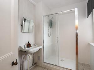 a white bathroom with a shower and a sink at Tan Y Coed in Menai Bridge