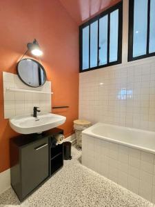 ein Badezimmer mit einem Waschbecken, einer Badewanne und einem Spiegel in der Unterkunft Duplex de caractère 50 m² in Moulins