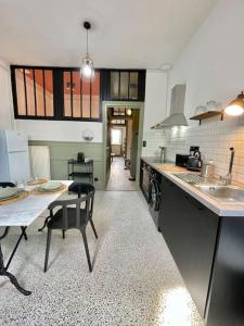 eine Küche mit einem Waschbecken und einem Tisch mit Stühlen in der Unterkunft Duplex de caractère 50 m² in Moulins