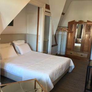 a bedroom with a white bed and a wooden cabinet at La Villa L'Argentine in Cabourg