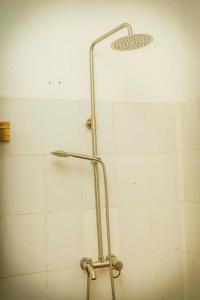 um chuveiro na casa de banho com azulejos brancos em Room in Guest room - Isange Paradise Resort em Ruhengeri