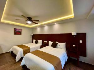 two beds in a hotel room with a ceiling fan at Hotel Puebla Plaza in Puebla