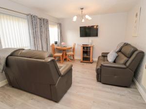 a living room with two leather chairs and a table at Primrose Cottage in Chathill