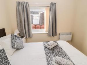 a bedroom with a white bed and a window at Primrose Cottage in Chathill