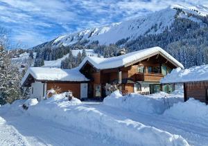 een huis bedekt met sneeuw voor een berg bij Ferienwohnung Jochum-Pfeiffer in Riezlern