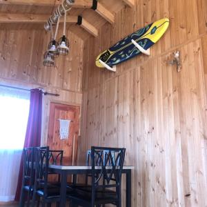 een eetkamer met een tafel en een surfplank aan de muur bij Comoda Cabaña en Pichilemu in Pichilemu
