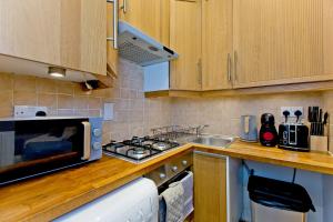 cocina con fogones horno de arriba junto a un fregadero en Imperial Earls Court Apartments, en Londres