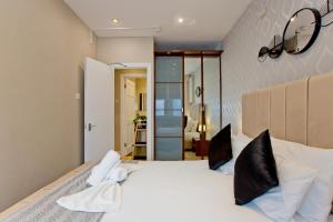 a bedroom with a large white bed with black pillows at Imperial Earls Court Apartments in London