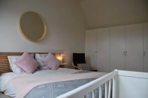 a bedroom with a bed with pink pillows and a mirror at Riposo in Poperinge