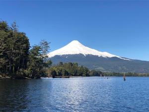 a snow capped mountain looms over a lake with a mountain in the background at Calma Lodge in Puerto Clocker