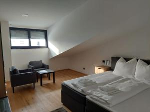 ein Schlafzimmer mit einem großen weißen Bett und einem Stuhl in der Unterkunft Pension Sunnseitn - Gasthof - Café - Weinkeller in Haslach an der Mühl