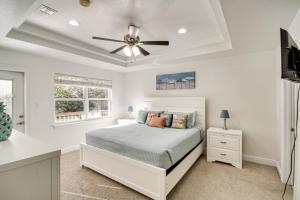 a white bedroom with a bed and a ceiling fan at Ideally Located Gulfport Condo Less Than 1 Mi to Beach! in Gulfport