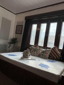 a bedroom with a large bed with windows at Feather Stays - 4 BHK Apartment in a Villa in Srinagar