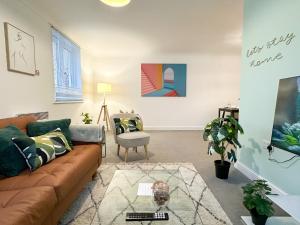 een woonkamer met een bank en een stoel bij Luxury 2 Bedroom City Centre Apartment - Secure Parking - Amazing location! in Canterbury