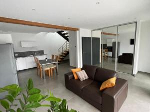 een woonkamer met een bruine bank en een tafel bij Les Duplex Solaires in Duppigheim