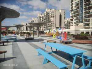 a park with blue benches and tall buildings at Down town new El alamein in El Alamein