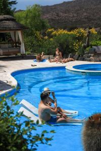 a man sitting on a towel in a swimming pool at El Carmelo Mountain Lodge in Potrerillos