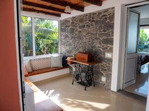 a room with a stone wall and a table and window at Casa dos Anjos in Ponta do Sol