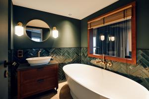 a bathroom with a tub and a sink and a mirror at Villa Viva - ein Haus das Brunnen baut in Hamburg